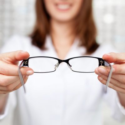 Closeup of optometrist, optician giving glasses  to try